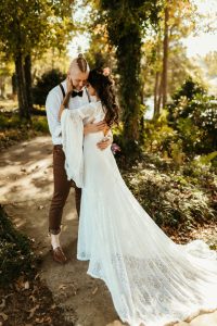 Bohemian bride on wedding day wearing a wedding dress from Carrie's in Georgia, Dress has long bell sleeves in lace.